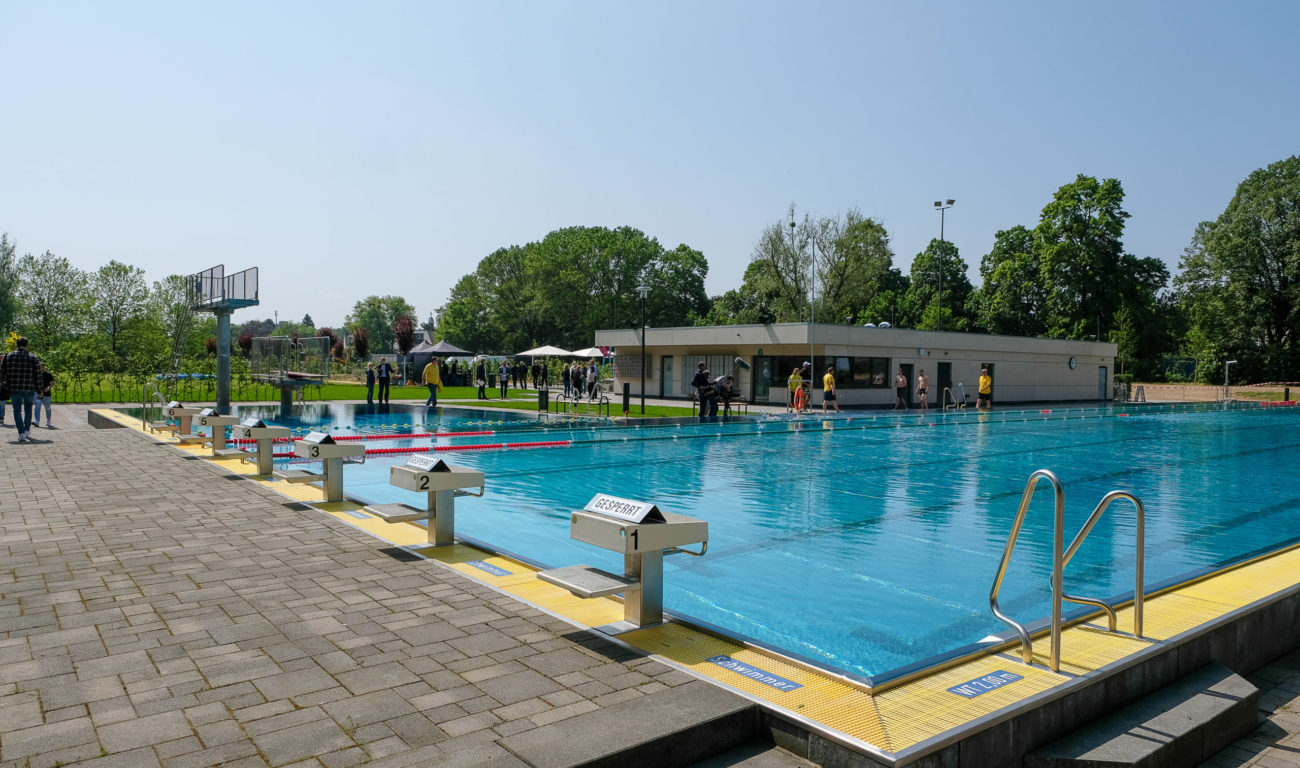 Das Foto zeigt den Blick auf die sechs 50-Meter-Bahnen des Sportbeckens und auf das neue Funktionsgebäude des Freibads in Benrath. (Foto: Landeshauptstadt Düsseldorf/Uwe Schaffmeister)