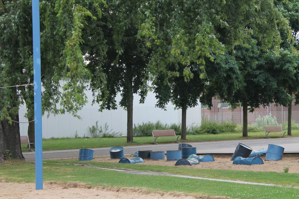 Alte Ölfässer liegen in einem Sandstück und laden zum chillen ein.