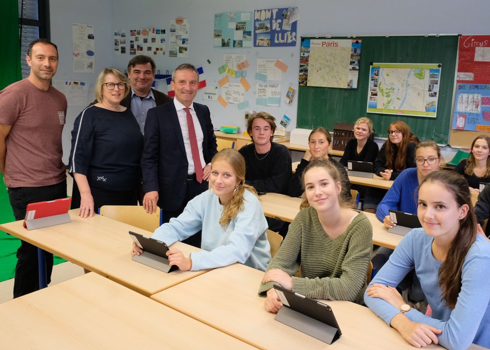 Freude beim Spanischkurs: OB Geisel (stehend r.) übergab mit Bezirksbürgermeister Karsten Kunert 180 iPads an das Marie-Curie-Gymnasium. Mit dabei Schuleiterin Kerstin Abs und Spanischlehrer Federico Rodriguez (l.). (Foto: Landeshauptstadt Düsseldorf/Wilfried Meyer)