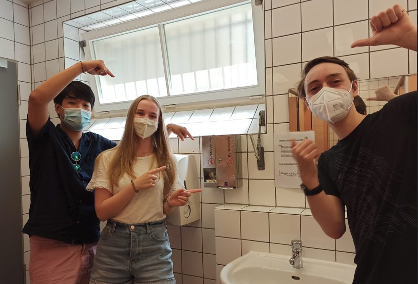 Wie der Jugendrat den Schulen kostenfreie Menstruationsprodukte brachte Die ersten Spender für Binden und Tampons hängen. Paul Ewe aus dem Jugendrat (rechts) hatte die Idee und freut sich über den Erfolg. (Foto: Jugendrat Düsseldorf)