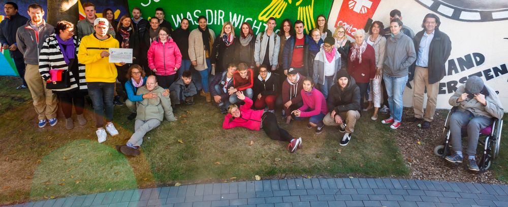 Schüler der Förderschule und der Berufsschule haben sich mit Bewohnern des Matthias-Claudius-Hauses vor der neu gestalteten Wand versammelt. Copyright: Provinzial Versicherung